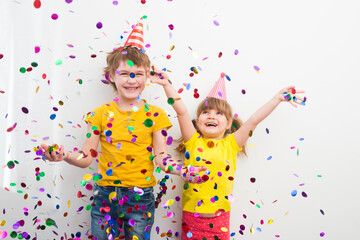 Obraz na płótnie Canvas happy two kids brother and sister with confetti on colored yellow background 