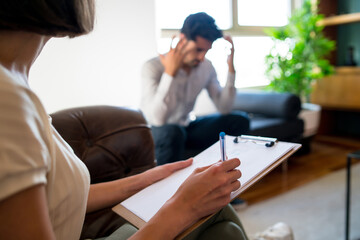 Psychologist taking notes during therapy session.