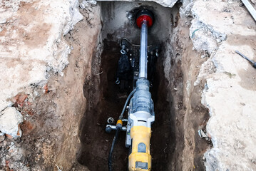 a diamond drill on an installation fixed to concrete blocks drills with water supply a hole in the foundation of a private house for sewerage