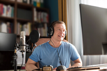 Man recording using headphones in front of microphone talking and recording podcast on computer at home studio. mass media 
