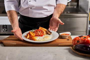 chef presents cooked breakfast dish to the guests, going to serve restaurant visitors,...