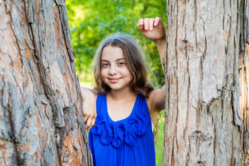 Girl long curly hair lean on tree trunk, summer camp