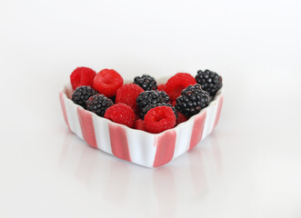 Red Raspberries and Blackberries in a Pink and White Bowl with White Background.