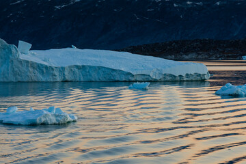 Greenland. Disko Bay. Icebergs at sunset in the calm water.