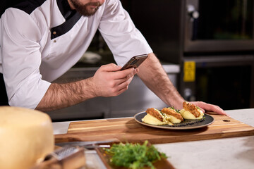 Cropped Chef Cook Take photo of Dish prepared by him, using smartphone. tasty yummy meal on plate is going to be served for restaurant guests