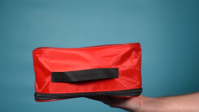 Closeup view 4k stock video footage of male hand holding red case of first aid medical kit 