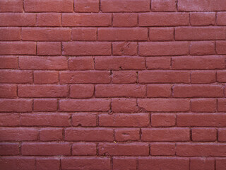 Obraz premium Red brick background partially casually painted over with paint or plaster. Textured surface of a modern industrial room finish. Cheap and simple painted brickwork.
