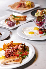 Big variety of delicious food on table flat lay, in restaurant. Beautifully and professionally cooked served meal for guests in rich restaurant. focus on fried crisps and bacon on plate