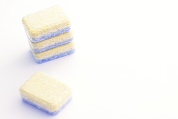 Yellow blue dish washer machine tablets on white. Domestic household tool