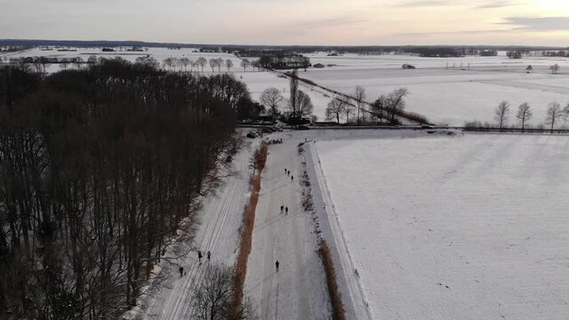Aerial shot, Dutch winter landscape, ice skating on frozen river, pan shot