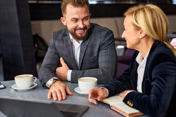 two business partners chatting over a cup of coffee, thinking and talking, discussing business ideas and projects, in restaurant