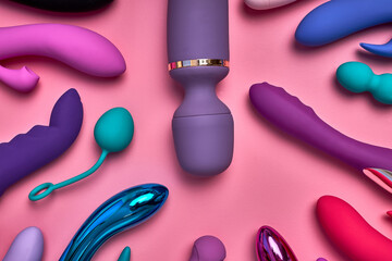 Fototapeta purple big phallus among small sex toys isolated on pink background, a lot of bright vobrators lie on pink paper, toys for relaxation and pleasure, romantic time. sex shop concept obraz