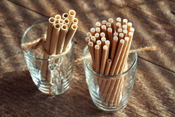 Paper straws in a glass, with bamboo straws in the background - zero-waste or ecology concept