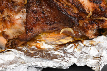 Obraz na płótnie Canvas baked meat and fried onions on a baking sheet, pork ham on foil and wooden background, home cooking