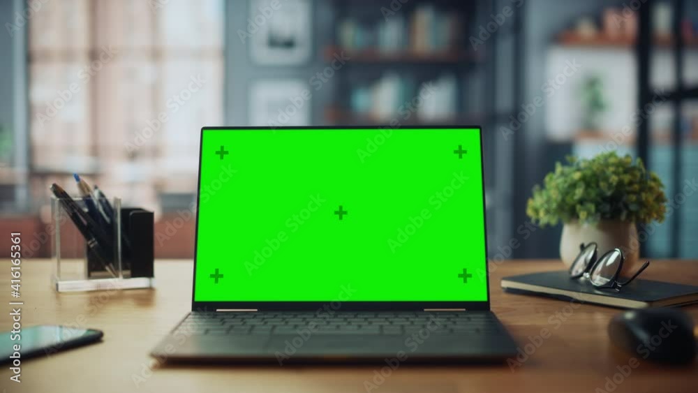 Poster laptop computer with mock up green screen display standing on the table in cozy living room. in the 