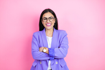 Young business woman wearing purple jacket over pink background with a happy face standing and smiling with a confident smile showing teeth with arms crossed
