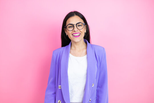 Young business woman wearing purple jacket over pink background with a happy face standing and smiling with a confident smile showing teeth