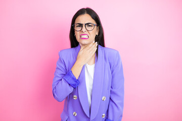 Young business woman wearing purple jacket over pink background touching painful neck, sore throat...