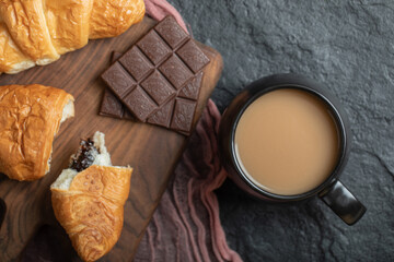 A cup of coffee with croissants and chocolate bars