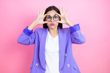 Young business woman wearing purple jacket over pink background Trying to open eyes with fingers, sleepy and tired for morning fatigue