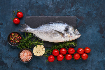Raw dorado fish with spices on a dark blue background. Mediterranean seafood concept. Top view, copy space