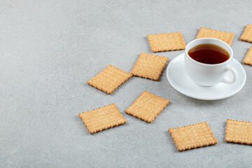 A cup of aroma tea with crackers on a gray background