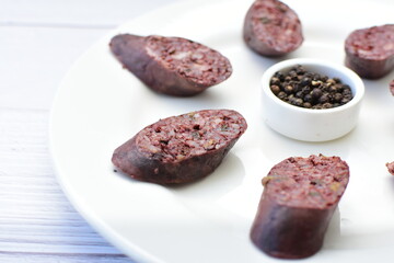 Morcilla Antioqueña, traditional Colombian sausage, covered with lemon and pepper on wooden background