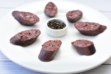 Morcilla Antioqueña, traditional Colombian sausage, covered with lemon and pepper on wooden background