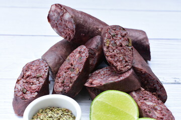 Morcilla Antioqueña, traditional Colombian sausage, covered with lemon and pepper on wooden background