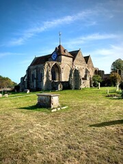 Fototapeta na wymiar Afternoon View of the Ancient 13th Century St Thomas the Martyr Parish Church With Gravestones, Trees, and Lawn, Winchelsea, England 