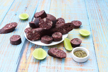 Morcilla Antioqueña, traditional Colombian sausage, covered with lemon and pepper on wooden background