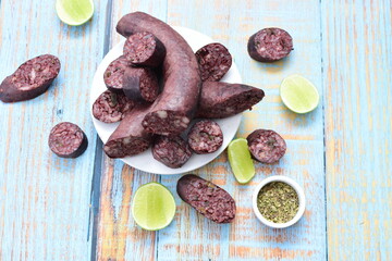 Morcilla Antioqueña, traditional Colombian sausage, covered with lemon and pepper on wooden background