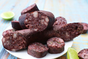 Morcilla Antioqueña, traditional Colombian sausage, covered with lemon and pepper on wooden background