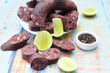Morcilla Antioqueña, traditional Colombian sausage, covered with lemon and pepper on wooden background