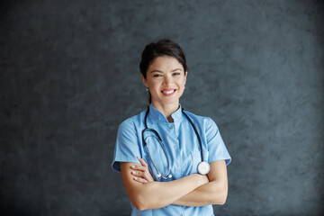 Smiling female doctor with stethoscope around neck standing with arms crossed. She is dedicated and experienced doctor.