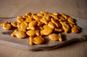fish shape close up golden cracker crunchy fishes piled heap wood kitchen cutting board studio