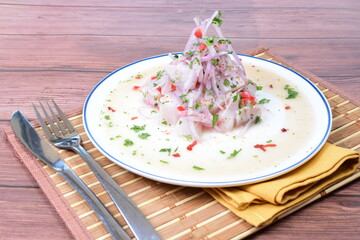 Traditional Peruvian ceviche with fish, onion, lemon, chili peppers, coriander, salt and pepper on wooden background