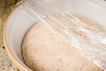 Sourdough rye bread rising in a bowl on the counter. Cover the bowl with plastic wrap that has been sprayed with a cooking spray to prevent sticking.