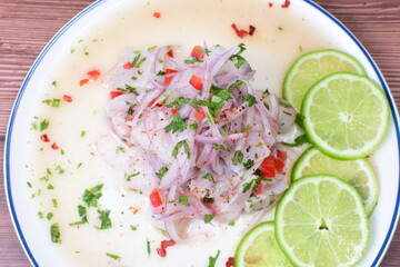 Traditional Peruvian ceviche with fish, onion, lemon, chili peppers, coriander, salt and pepper on wooden background