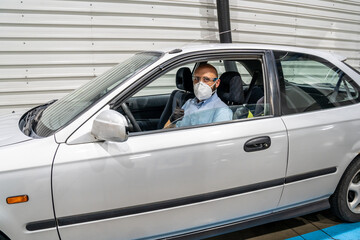 A technician in a periodic inspection of a vehicle showing thumbs up inside a car