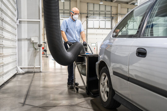 A technician placing a smoke absorber prior to an emission control of a periodic inspection of a vehicle