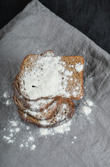 Slices of brown bread with flour on a gray tablecloth