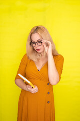 Blond woman in glasses holding yellow book