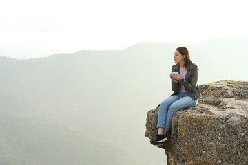 Woman drinking coffee contemplating views from cliff