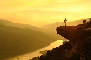 Woman silhouette breathing fresh air in the top of a cliff