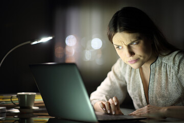 Suspicious woman checking laptop content in the night - obrazy, fototapety, plakaty