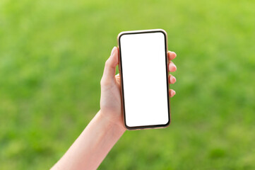 Hand holding mobile phone against natural green background