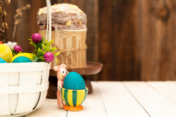 Easter background with basket full of colorful eggs, easter bunny and easter cake (aka: Orthodox sweet bread, kulich or Paska). Copy space for text. Wooden background.
