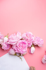 pink roses with white envelope and macaroons around pink background. life style concept. flat lay