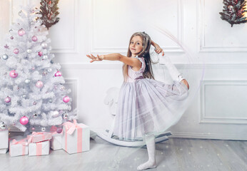 Little girl dancing around a white Christmas tree